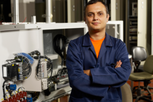 Engineer standing confidently next to an electrical control system.