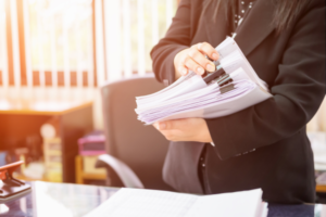 Person organizing and handling documents in an office environment.