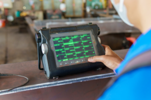 Technician using a portable diagnostic device for testing metal structures.