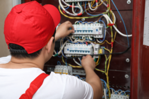 Technician repairing a circuit breaker in an electrical cabinet.