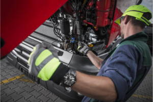 Mechanic inspecting a truck engine, close-up on maintenance work.