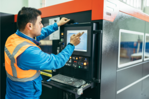 Operator using a touchscreen on industrial equipment in a workshop.